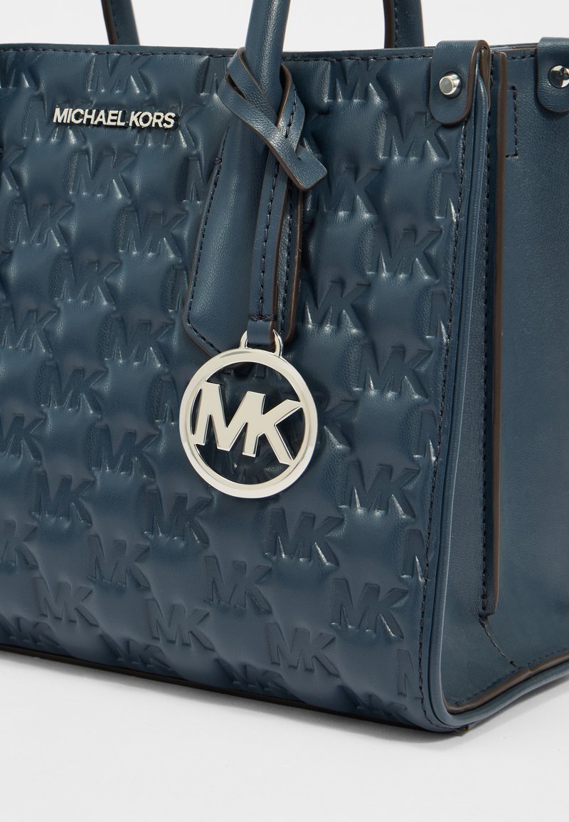 Borsa a mano in pelle blu con motivo a logo MK in rilievo, charm MK in argento e doppi manici. Presenta un design strutturato e cuciture a contrasto.