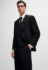 Black three-piece suit featuring a tailored jacket, waistcoat with buttons, and slim-fit trousers. Smooth fabric and classic lapels.