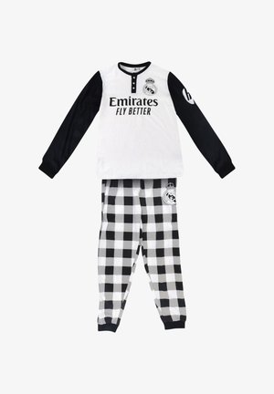 Maglia a maniche lunghe bianca e nera del Real Madrid con testo "Emirates Fly Better", abbinata a pantaloni a scacchi bianco e nero con il logo del club.