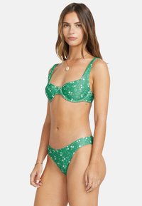Grön bikinitopp med blommönster, en strukturerad bygelöverdel med breda band och låga bikinitrosor med matchande design.