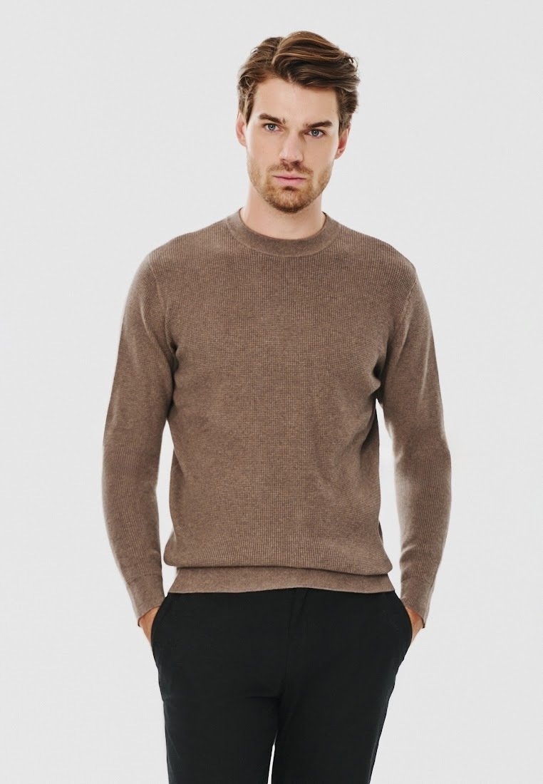 Brązowy sweter dzianinowy z okrągłym dekoltem, długimi rękawami i fakturowanym wzorem; w zestawie z ciemnymi spodniami.