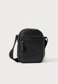 Mala tiracolo em pele preta com textura canelada, bolso frontal com fecho de correr, alça ajustável e design arredondado. Adequada para uso diário.