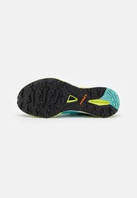 Suola di scarpa da trail running, con una superficie in gomma nera caratterizzata da tasselli multidirezionali, dettagli in verde menta e un logo arancione.