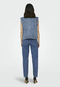Džínová vesta s krátkými rukávy a zadním dílem se sektorem, doplněná vysokým pasem a rovnými nohavicemi džínů ve středně modrém odstínu.