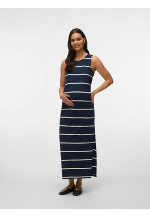 Rasedusnaine tumesinine-valge triibulise varrukateta maksikleidi kandmas, naeratades ja õrnalt oma kõhtu hoides, jalas mustad kingad.