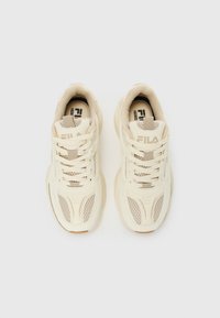 Et par beige FILA-sneakers med mesh-paneler og tykke såler sett ovenfra på hvit bakgrunn.
