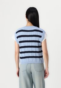 Blauer gestrickter Strickwesten mit strukturierten Zopfmustern, versehen mit dunkelblauen Streifen. Kurze Ärmel, cropped Design und gerippter Saum.