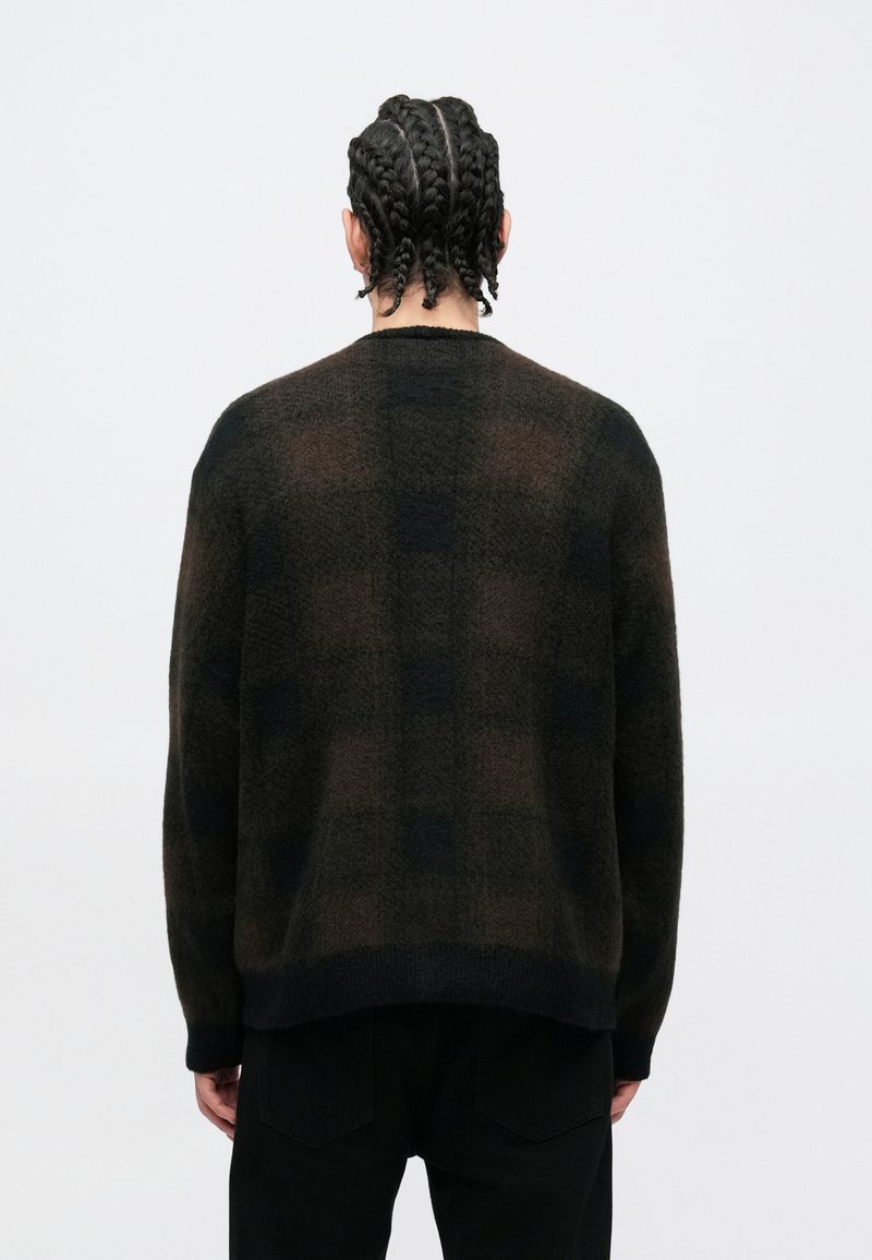 Brown and black checkered knit sweater with a soft texture, relaxed fit, and a slightly longer back hem. Ribbed cuffs and neckline.