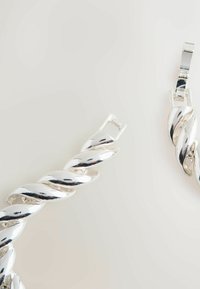 Silver twisted metal earrings with a shiny finish, featuring a unique spiral design and a secure clasp for fastening.