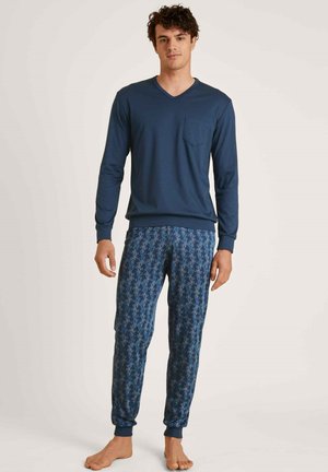 Haut à manches longues navy avec un col en V et une poche, associé à un pantalon de pyjama bleu à motifs avec un design de feuilles et des poignets élastiques aux chevilles.