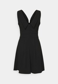 Černé bezrukávové šaty s hlubokým výstřihem do V a širokým klopovým límcem, přiléhavým pasem a rozšířenou sukní na bílém pozadí.