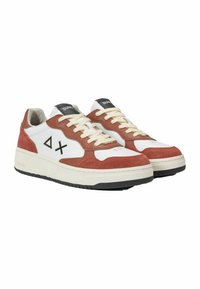 Sneaker basse in suede bianco e ruggine con lacci beige, dettagli neri e logo sulla linguetta. Presentano una suola testurizzata e forma arrotondata.