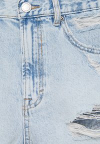 Světlé modré vintage džíny s roztrhanými otvory, mají zapínání na knoflík, kontrastní švy a vybledlou texturu.