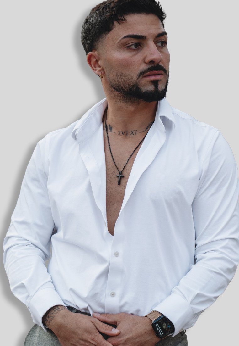 White button-up shirt with an open collar, featuring long sleeves and a smooth texture. Black cross necklace and smart watch as accessories.