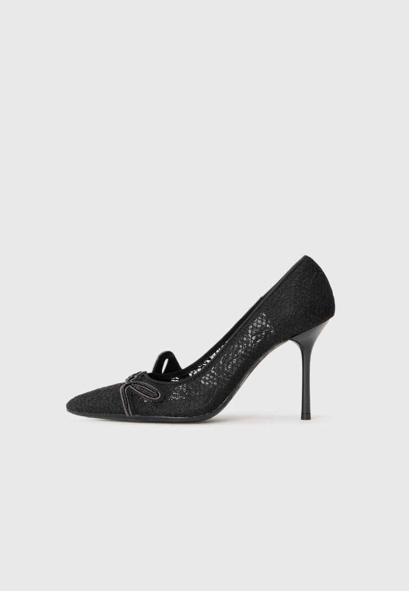 Schwarze Spitzen-Pumps mit hohen Absätzen und spitzem Zehenbereich, ausgestattet mit einem dekorativen Schleifendetail und dünnem Stiletto-Absatz. Strukturierte Spitzenoberfläche.