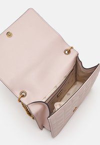 Růžová kožená kabelka s prošívanou texturou, zlatým kováním a hladkou vnitřní podšívkou se subtilním logem; otevřený a prostorný design.