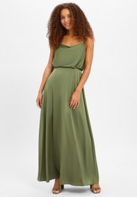 Robe maxi vert olive avec un décolleté drapé et une taille cintrée. Tissu lisse et fluide, design à bretelles, associé à des talons assortis.