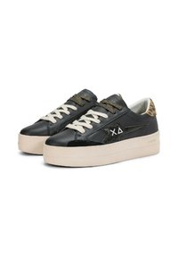 Baskets en cuir noir avec une semelle épaisse de couleur crème, présentant des lacets métalliques et un accent en imprimé léopard au niveau du talon, logo étoile sur le côté.