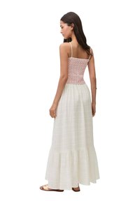 Maxiklänning med en åtsittande, texturerad röd bodice och en flödande vit kjol. Har spagettiband och en volangkant.