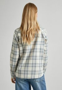 Blå og beige ternet skjorte lavet af blødt stof, med lange ærmer, knapmanchetter og en afslappet pasform, samt en lige nederkant.