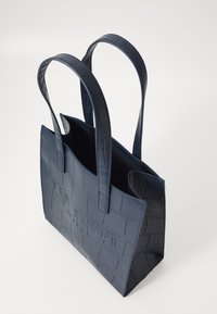 Borsa tote in finta pelle blu navy con un motivo goffrato a coccodrillo e logo impresso, dotata di due manici robusti e apertura superiore.
