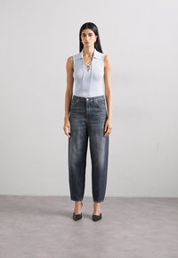 Lyseblå ribbestrikket ermeløs topp med krage og blonde-detall, kombinert med høytlivede mørkeblå denimjeans og svarte spisse hæler.