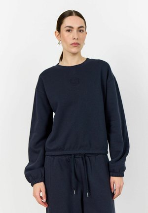Navy blue sweatshirt in soft fabric with long sleeves, ribbed cuffs, and a subtle embossed logo on the chest, featuring a relaxed fit.