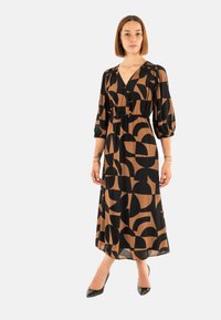 Vestido largo en negro y marrón con patrones geométricos, escote en V, cintura elástica y mangas globo, hecho de una tela ligera.