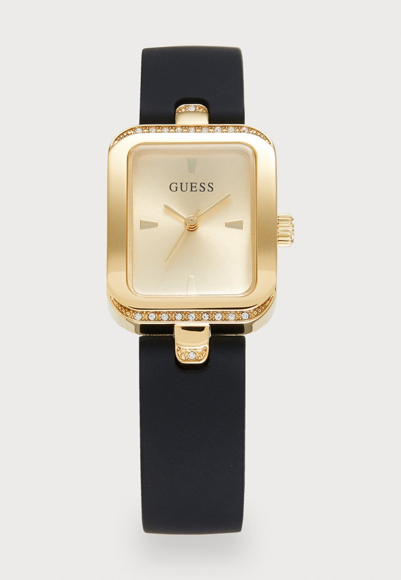 Gold rectangular watch with a smooth black silicone strap, crystal accents around the bezel, and a simple gray dial with gold hands and markers.