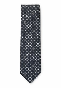 Cravatta blu navy con un motivo geometrico di piccoli punti bianchi e logo, realizzata in tessuto testurizzato, presenta un'estremità appuntita e un design stretto.