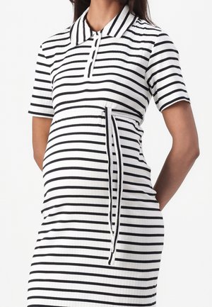 Pregnant woman wearing a black and white horizontal striped polo dress with short sleeves and a waist tie.