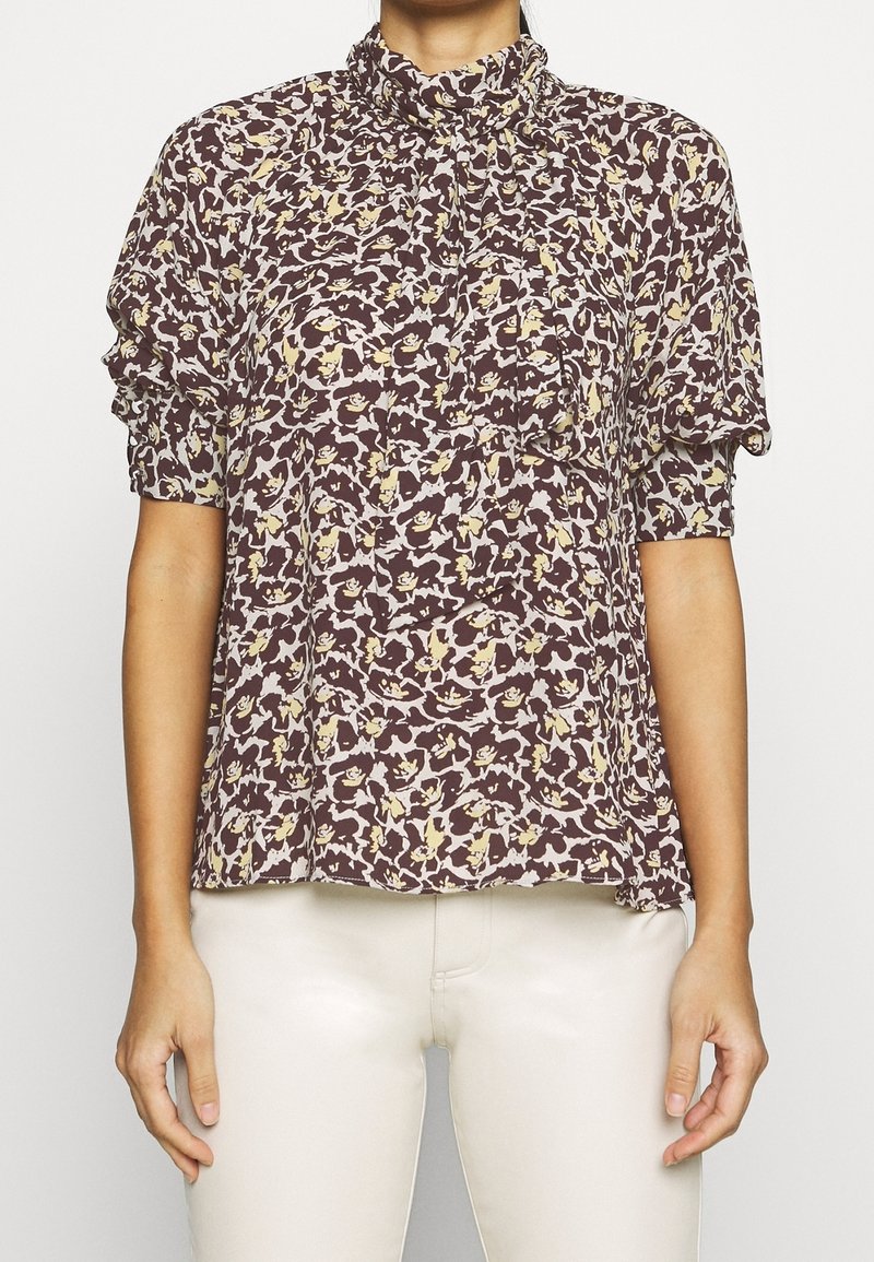 Braune Bluse mit floralen Mustern, Rüschensaum am hohen Kragen und kurzen Ärmeln. Verfügt über ein texturiertes Druckbild mit cremefarbenen und gelben Blumenmustern.