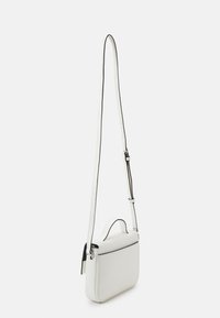 Bolso cruces de piel blanca con forma rectangular, ribete negro, correa ajustable y pequeña asa superior. Textura suave, diseño minimalista.