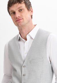 Gray textured vest with a fitted design, two buttons, and a breast pocket. Worn over a white shirt with button detailing.
