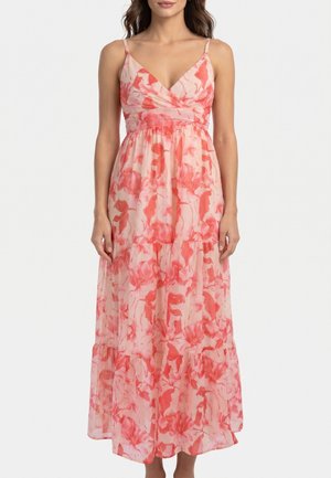 Vestido largo sin mangas con estampado floral en rosa y coral, escote en V y cintura fruncida en una mujer de pie sobre un fondo blanco.