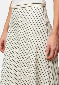 Een knie-lange crèmekleurige rok met zwarte diagonale strepen, vervaardigd uit een textuurstof en voorzien van een tailleband met een contrasterende rand.