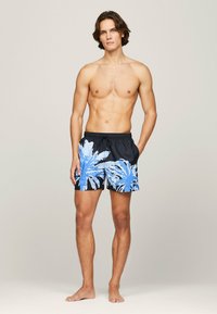 Costumi da bagno da uomo neri con stampa tropicale di foglie di palma blu. Presentano una vita elastica con cordoncino. Tessuto leggero.