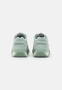 Zapatillas de ante verde claro con un acabado texturizado, que cuentan con un tobillo acolchado, suela de dos tonos y un diseño elegante.