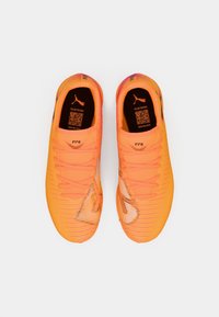 Helle orangefarbene Fußballschuhe mit strukturiertem synthetischem Obermaterial, kontrastierenden dunklen Akzenten und Schnürsystem. Mit Puma-Logo auf der Zunge.