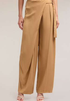 Pantalones de pierna ancha en suave tejido beige con una textura lisa, que presentan un diseño envolvente, cierre lateral de cremallera y un acento de cinturón.