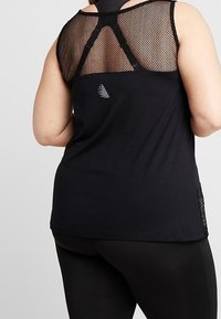 Zwarte sportieve tanktop met een mesh achterpaneel, ronde halslijn en een zijaccent. Het materiaal lijkt lichtgewicht en heeft een gladde textuur.