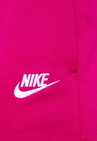 Rosa bomulls tyg med en broderad vit Nike-logotyp. Tyget har en slät textur med en figurnära design.