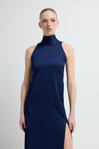 Tmavě modré saténové šaty s vysokým límcem, bez rukávů a s bočním rozparkem. Hladká textura s elegantní, štíhlou siluetou.