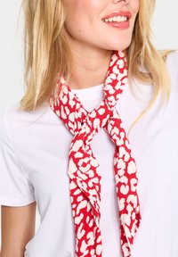 Fular roșu și alb cu model, din țesătură ușoară, legat la gât, având un design abstract îndrăzneț cu forme neregulate.