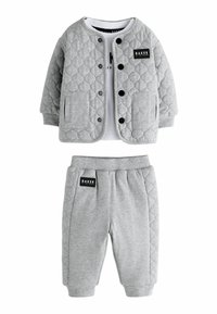 Hallhallikate hall vest mustade nuppude ja taskutega, koos hallide pükstega, millel on must sildiga. Pehme kangas ja baasdisain.