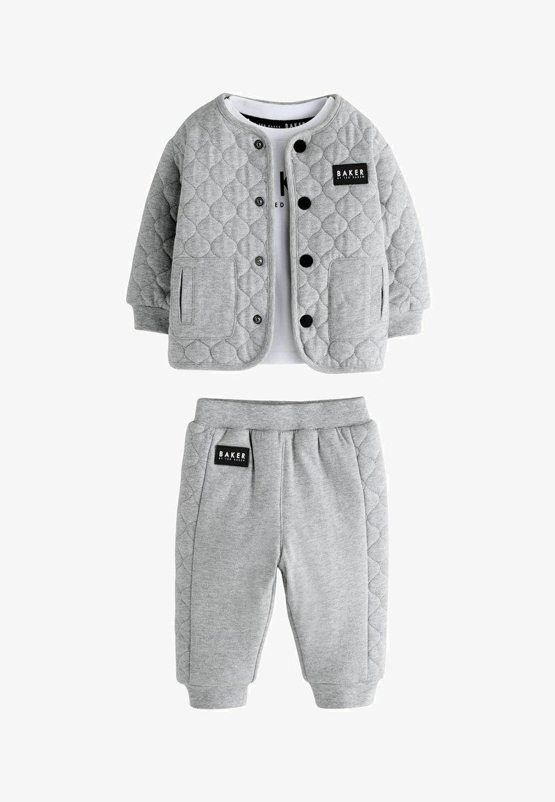 Hallhallikate hall vest mustade nuppude ja taskutega, koos hallide pükstega, millel on must sildiga. Pehme kangas ja baasdisain.