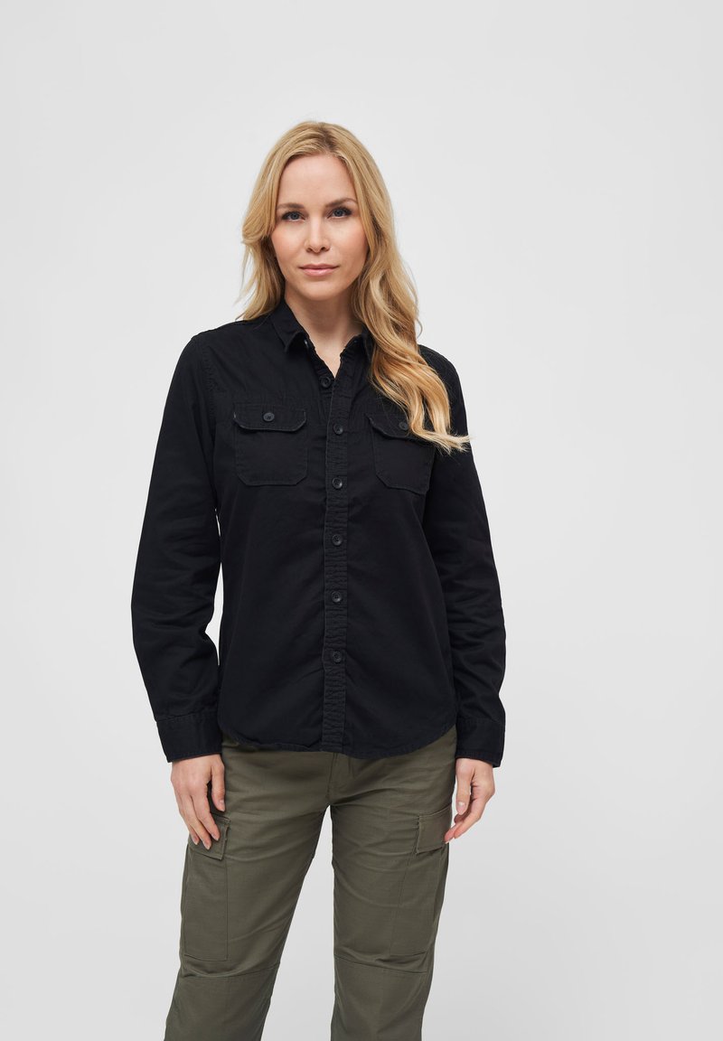 Camicia nera a maniche lunghe con bottoni e due tasche sul petto, abbinata a pantaloni cargo verde oliva, con una vestibilità comoda e tessuto testurizzato.