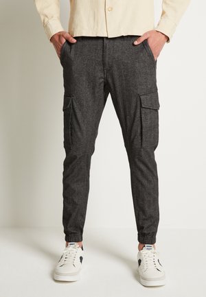 Kolvärda cargobyxor med elastiska muddar, med sidfickor och en texturerad tyg. Matcherade med vita sneakers för kontrast.