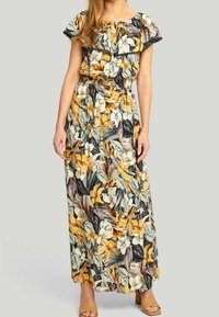 Maxi kjole med blomsterprint bestående af gule og hvide blomster på en mørk baggrund, korte flæseærmer og elastisk talje.