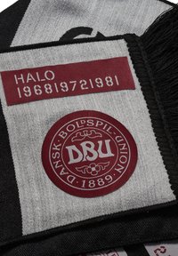 Grå og sort tørklæde med frynser, der har burgunderfarvede pletter med teksten "HALO" og "DBU" i en rund emblematisk form samt teksten "1968 19721981."